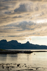 Dramatic evening storm clouds at stunning evening over the beach at Mjelle in Northern Norway pouring rain over the bay