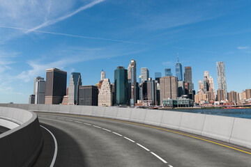 Empty curved road with New York City skyline in the background.