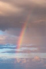 Rainbow coming out of stormy clouds under the rain 