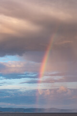 Rainbow coming out of stormy clouds under the rain 