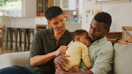 Male Couple Caring Adults Engaging With a Sleeping Child in a Cozy Living Room 