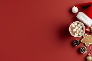 Flat lay of holiday hot chocolate with marshmallows, cookies, and pine cones on red background. Christmas celebration concept. Design for greeting cards and banners. With copy space