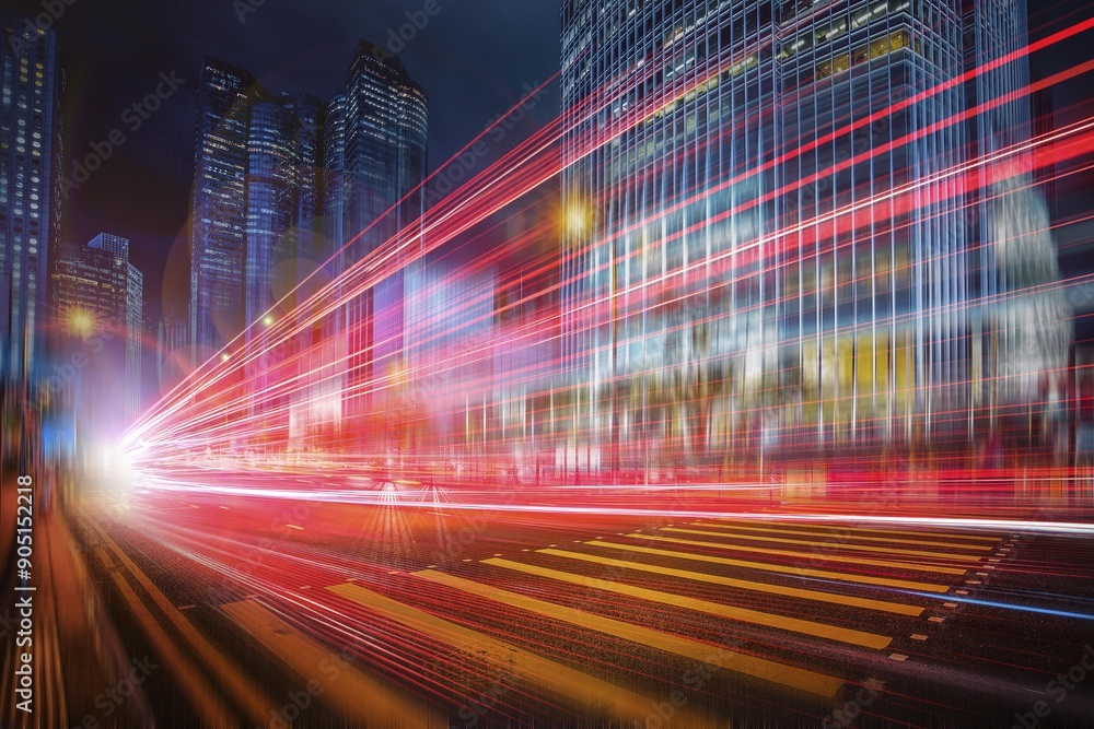 Wall mural A city street at night with tall buildings in the background, illuminated by bright red and white streaks of light from passing cars.