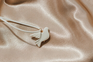 bijouterie white bird made of polymer clay on the background of silk shiny fabric