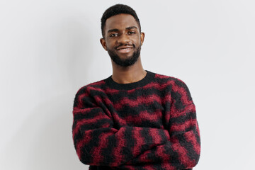 Obraz premium Confident young man in stylish red and black sweater standing against a plain white background