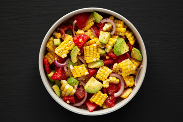 Healthy Fresh Corn Salad in a Bowl on a black background, top view. Flat lay, overhead, from above.