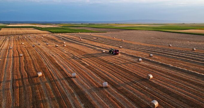 Tractor baler in action on a harvested wheat field