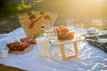 Beautiful cozy autumn picnic by the lake with fruits, pastries and wine. Sun rays. Sunset.