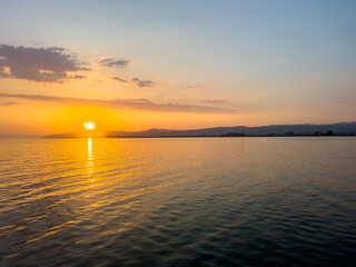 A group of adult friends are standing on the pier by the sea at sunset, friendship themed concept