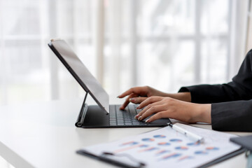 A woman is typing on a tablet computer