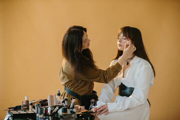  Makeup Artist Applies Concealer to a Model's Face, Preparing for a Photo Shoot