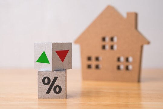 Wooden blocks percentage sign, arrow up and down with house model background. Central bank FED control interest rate increase or decrease effect to house price, monthly payment, buying home concept.