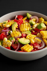 Healthy Fresh Corn Salad in a Bowl on a black background, side view. Close-up.