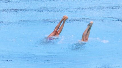 Synchronized or artistic swimming duet performing synchronized legs movement in swimming pool