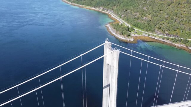 Aerial drone view of bridge in Northen Norway with cars driving on top and sharp mountains in the background