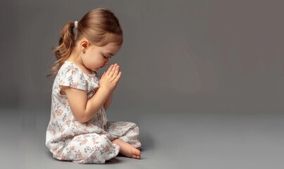 Fototapeta premium A young girl with curly hair prays with her eyes closed and hands folded, representing innocence, faith, and contemplation in a serene and focused moment