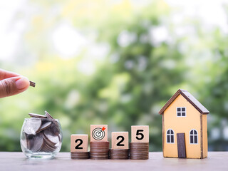 Miniature house, Wooden blocks with the number 2025 and stack of coins. The concept of saving money for house, Property investment, House mortgage, Real estate in year 2025