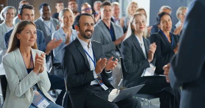 Back View Of Startup CEO Gesturing And Pitching Innovative Product Or Service to Room Full of Diverse Investors. Business People Applauding and Smiling At International Technology Forum. Slow Motion.