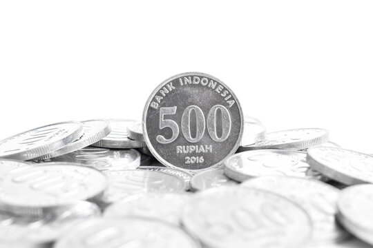 Indonesian five hundred rupiah coin standing with other coins isolated on plain white background. National currency. Indonesian rupiah coin. Copy space.