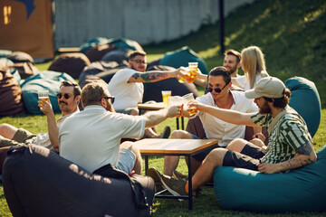 Relaxing moment, Happy young people, friends gathering outdoors for picnic, sitting on bean bag...
