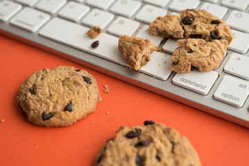 Broken chocolate chip cookies on keyboard computer background. Cookies website internet homepage policy accpeted or blocks, technology internet website concept.