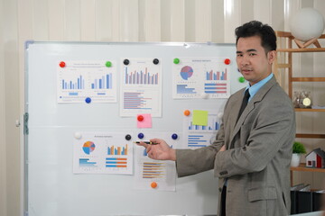 Fototapeta premium Asian male accountant working on table calculating taxes from annual financial documents, analyzing company budget report graphs. Assigned accounts receivable production control