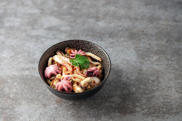 Mix of sea food - mussels, squid, octopus, shrimp in a bowl, lemon and soy sauce. Top view.