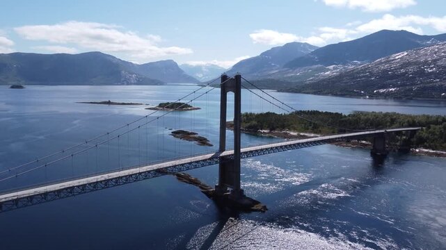 Aerial drone view of bridge in Northen Norway with cars driving on top and sharp mountains in the background