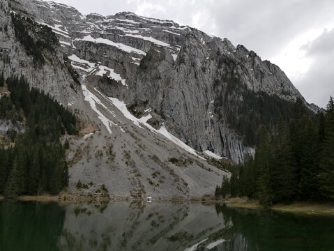 Massif of Bargy and lac Benit near Cluses in Haute Savoie, with cloudy weather and dramatic atmosphere and mirror effect. Alpine lake landscape