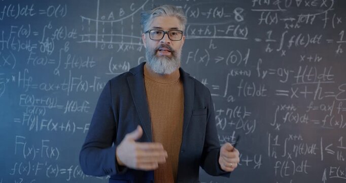 Portrait of maths teacher speaking and showing formula on chalkboard teaching during virtual lesson in online school. Education and people concept.