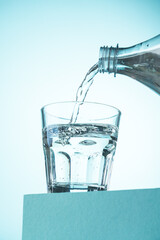 Pouring of water in glass on blue.
