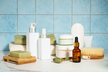Natural cosmetic products in the bathroom, blue background. Soap, mask, face cream, serum bottle,...
