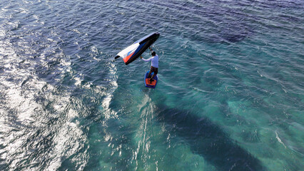 Aerial drone high speed tracking shot of athlete racing in wind surfing Hydro foil surf board in...