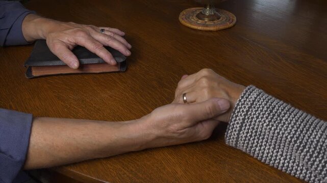 A married couple holding hands while praying