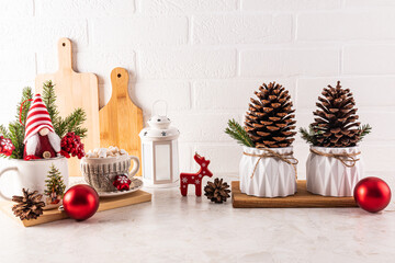 Two large cedar cones in a festive planter, a New Year's gnome among the branches of a spruce tree, cones on the kitchen countertop. Christmas kitchen