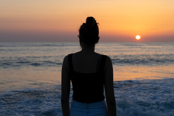 girl or woman on the beach towards a beautirful sunset