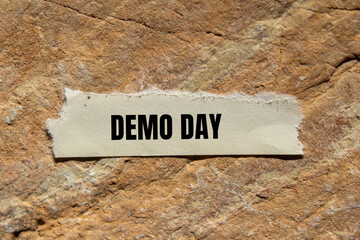 Demo day message written on ripped torn paper piece on stone background. Conceptual demo day...