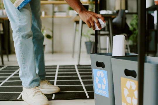 Unrecognizable male office worker throwing crumpled piece of paper into plastic recycling bin