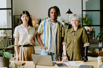 Medium long shot of three diverse gen Z coworkers posing for camera at work in modern eco-friendly...