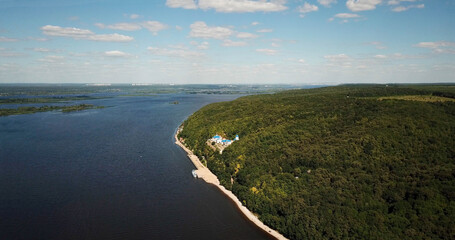 Monastery in the forest on the hilly bank of the river