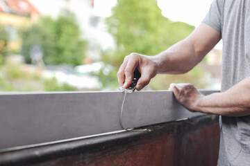 The hands Caucasian holds a construction knife in his hands and cleans plastic from silicone