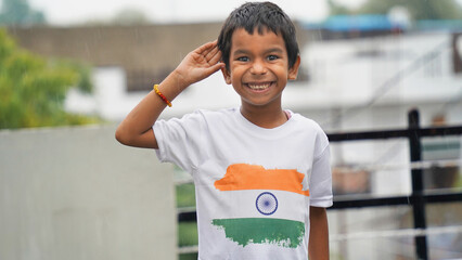 Little boy giving salute, wearing indian tricolor flag Tshirt and face painted with Indian flag colours. Indepence day celebration or Republic day.