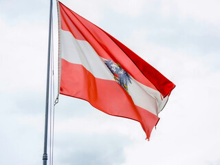 The national flag of Austria waves gracefully and proudly against a stunning natural backdrop of landscape beauty