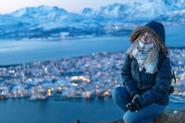 Fototapeta premium a blonde female woman traveler on top of the mountain in tromso norway in winter