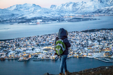a blonde female woman traveler on top of the mountain in tromso norway in winter