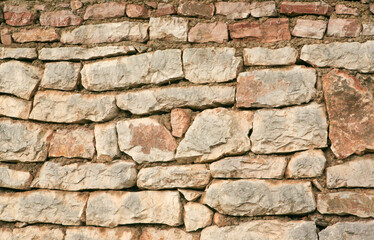 Background of a stone wall made of large stones without mortar, close-up. Stoney texture for publication, design, poster, post, screensaver, wallpaper, cover, website. High quality photo