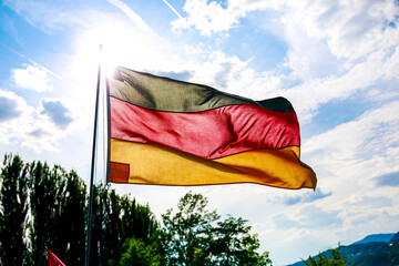 An eyecatching and vibrant German flag is waving gently in the wind against a backdrop of a cloudy...