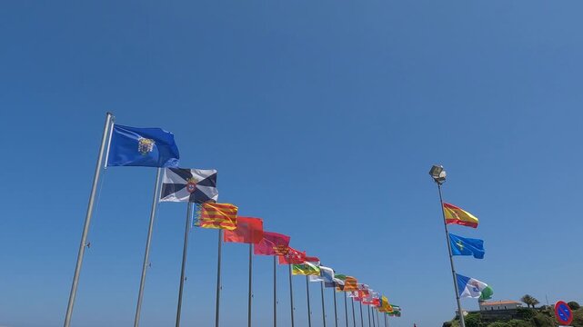 Conjunto de todas las banderas correspondientes a las comunidades aut&oacute;nomas de Espa&ntilde;a ondeando al viento en el puerto de Cudillero