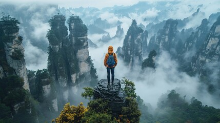 Obraz premium Hiker Standing on Mountain Peak Overlooking Foggy Clouds in Early Morning Light