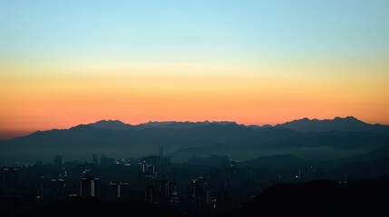Obraz premium Tranquil Cityscape Silhouette with Majestic Mountain Range in the Distance